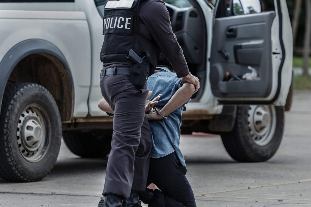 police is arresting a man in middle of a street